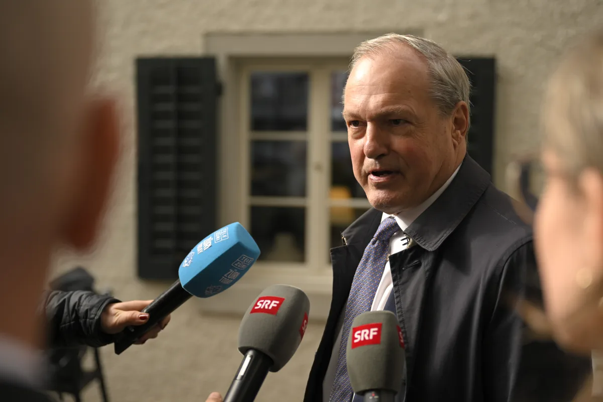 Kündig im Anzug vor drei Mikrofonen.